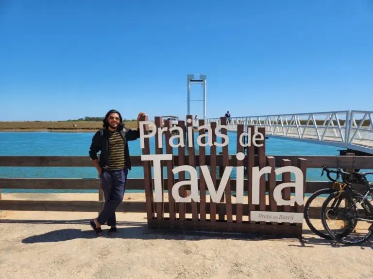 Monowar Hossain beside the Praias de Tavira sign at Praia do Barril in the Algarve, Portugal